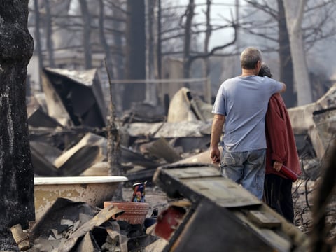 Richard and Kathie Reeves embrace as they stand in the remains of the home of close friends that was destroyed in a wildfire several days earlier, Tuesday, Sept. 15, 2015, in Middletown, Calif.
