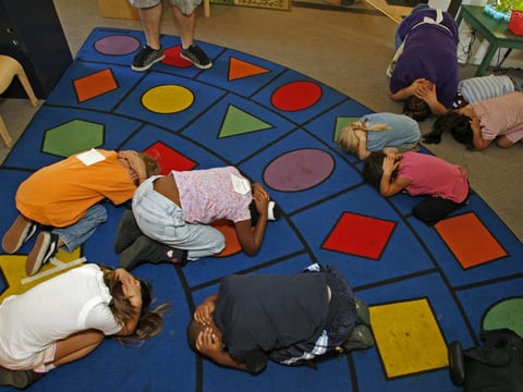 FILE - In this Nov. 13, 2008 file photo, school children practice their "drop, cover and hold" technique, as they participate in the "Great Southern California Shakeout" earthquake drill.