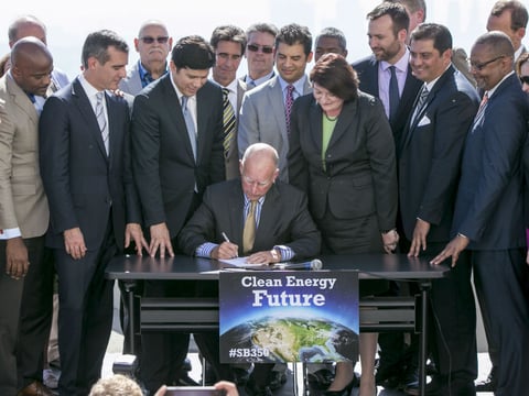 California Gov. Jerry Brown, sitting center, surrounded by government officials, signs landmark legislation, bill SB350 by Senate President pro Tempore Kevin De Leon, third from left, to combat climate change.