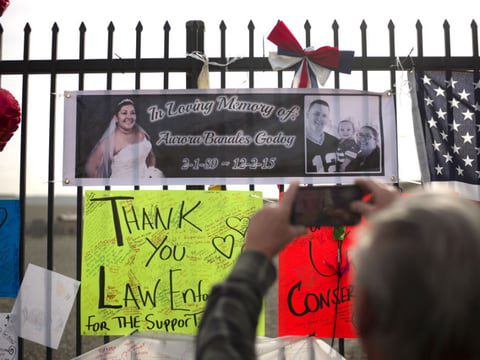 A man takes pictures of a banner showing photos of Aurora Godoy, one of the victims in last week's fatal shooting that killed 14 people at the Inland Regional Center, Wednesday, Dec. 9, 2015, in San Bernardino, Calif. 