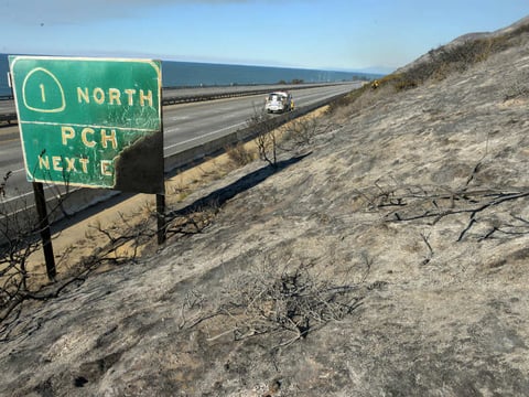Parked on a closed US Highway 101, a Santa Barbara County Fire Department fire engine and crew douse a hot spot while working a Solimar wildfire in Ventura County, Calif. on Saturday, Dec. 26, 2015.