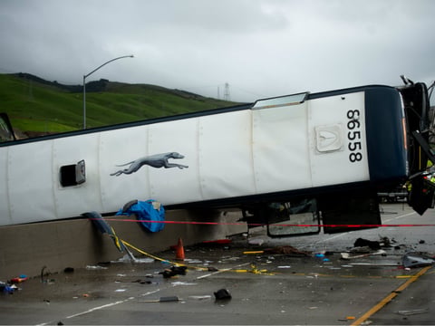 An overturned Greyhound bus rests atop a Highway 101 divider following a crash on Tuesday, Jan. 19, 2016, in San Jose, Calif. A Greyhound bus carrying 20 passengers rolled onto its side during a rainy Tuesday morning commute, killing at least two.