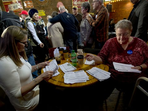 In this Jan. 25, 2016, photo, volunteers sort through commitment to caucus for Democratic presidential candidate Hillary Clinton cards during a campaign event at the Smokey Row in Oskaloosa, Iowa.