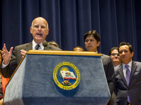 California Gov. Jerry Brown, left at podium, addresses members of the media, before signing a bill creating highest statewide minimum wage at $15 an hour by 2022 at the Ronald Reagan building in Los Angeles on Monday, April 4, 2016. 