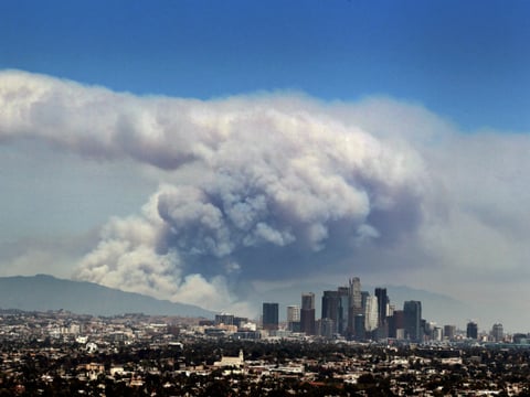 Smoke from wildfires burning in Angeles National Forest fills the sky behind the Los Angeles skyline on Monday, June 20, 2016.