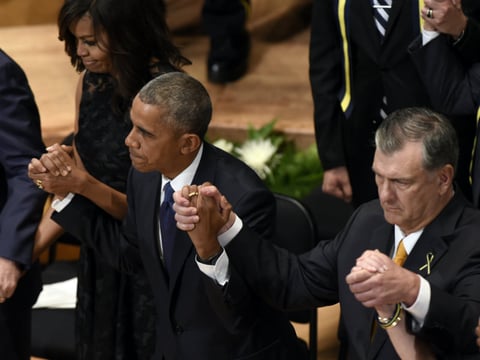 President Barack Obama holds hands with Dallas Mayor Mike Rawlings, right, and first lady Michelle Obama during an interfaith memorial service for the fallen police officers and members of the Dallas community on July 12, 2016. 