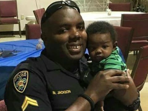 A photo provided by Trenisha Jackson shows her husband, Baton Rouge police officer Montrell Jackson, holding his son, Mason, at a Father's Day event for police officers in Baton Rouge, La. Montrell Jackson and two other officers was killed Sunday.