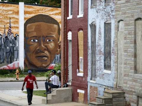 People walk by a mural depicting Freddie Gray in Baltimore on June 23, at the intersection where Gray was arrested in 2015. Prosecutors in Baltimore have dropped all remaining charges against police officers related to Gray's death while in custody.