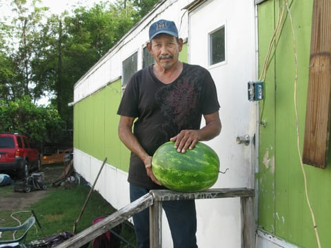 Justino DeLeon, 58, stands in front of his home in Pharr, Texas. A former watermelon picker; he retired from farm work when he fell off a melon truck and hurt his arm.