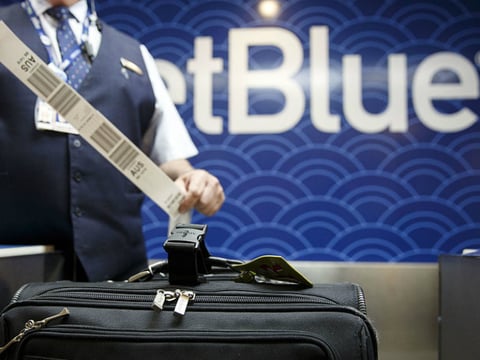 A JetBlue Airways Corp. employee tags a travelers bag at the ticket counter inside Long Beach Airport in Long Beach, Calif.