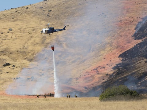 A California Highway Patrol helicopter drops water on a fire caused by the crash of a U.S. Air Force U-2 spy plane in the Sutter Butte Mountains, Tuesday, Sept. 20, 2016, near Yuba City, Calif.