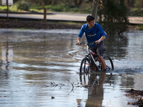 Rising river levels don't stop Ethan Belnap, 15, of Sacramento from riding his bike through a flooded parking lot on the American River Parkway on Friday, Dec. 16, 2016. 