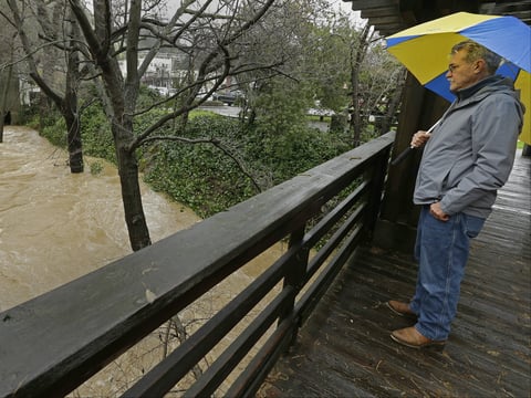 A man stands on a bridge as he watches the level of the San Anselmo Creek Tuesday, Feb. 7, 2017, in San Anselmo, Calif. 