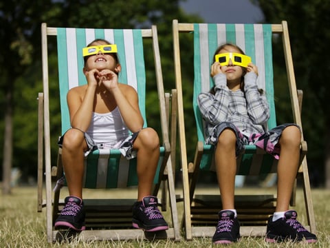 Neza Pintaric, 9 and sister Ula, 11, right, from Slovenia watch the partial eclipse of the sun through solar glasses in Hyde Park in central London, Friday August 1, 2008.
