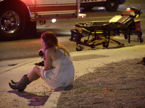 A woman sits on a curb at the scene of a shooting outside of a music festival along the Las Vegas Strip, Monday, Oct. 2, 2017, in Las Vegas. Multiple victims were being transported to hospitals after a shooting late Sunday on the Las Vegas Strip.