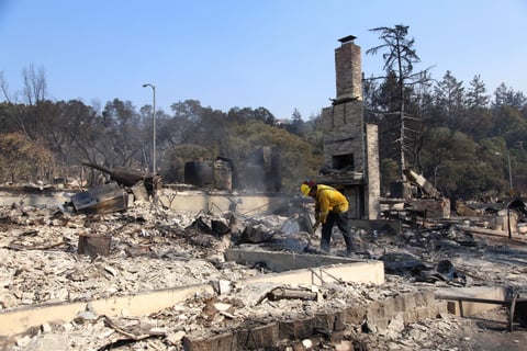 Berkeley firefighter Matt George picks through the ash of a Santa Rosa neighborhood looking for smoldering materials after deadly fires swept through the area in October 2017.