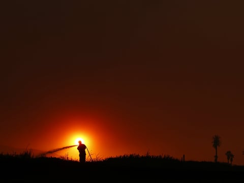 Firefighter Dan Whelan is silhouetted against the sun as he battles a wildfire burning near Faria State Beach in Ventura, Calif., on Thursday.