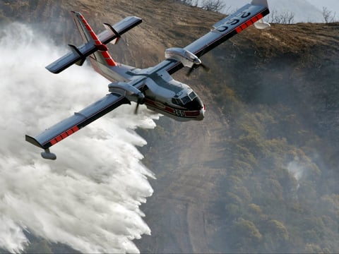 In this photo provided by the Santa Barbara County Fire Department, a Bombardier 415 Super Scooper makes a water drop on hot spots along the hillside east of Gibraltar Road in Santa Barbara, Calif., Sunday morning, Dec. 17, 2017. 