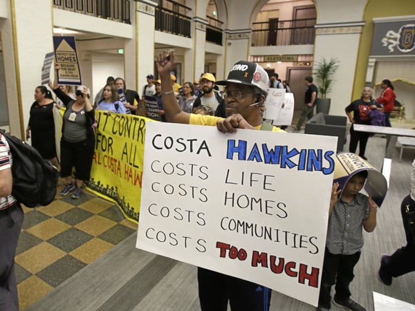FILE — In April 2018, Billy Martin, right, joined dozens of other supporters of a rent control initiative who marched into an office building where the California Association of Realtors is located calling for more rent control.