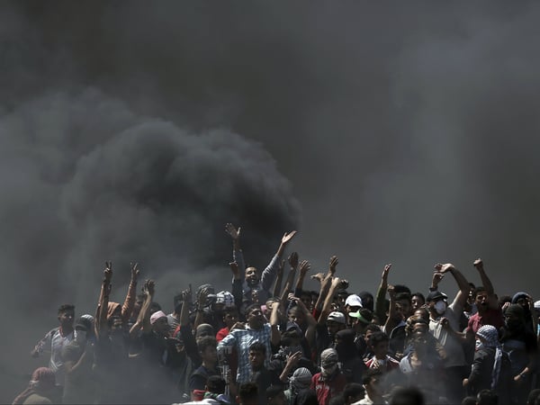 Palestinian protesters chant slogans as they burn tires during a protest on the Gaza Strip's border with Israel, Monday, May 14, 2018. 