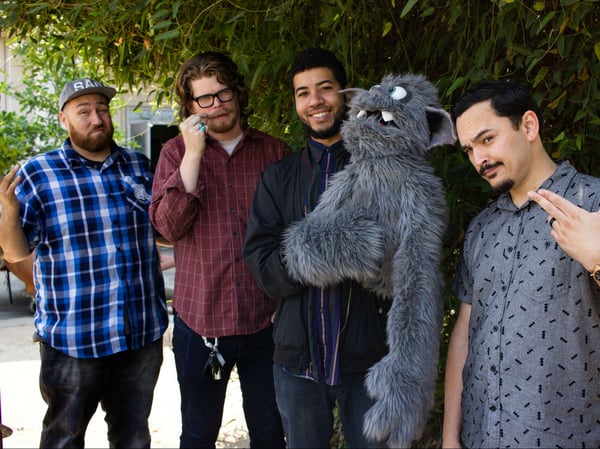 Monsters and Thieves pose with their mascot puppet, Cecil, in the CapRadio Garden.