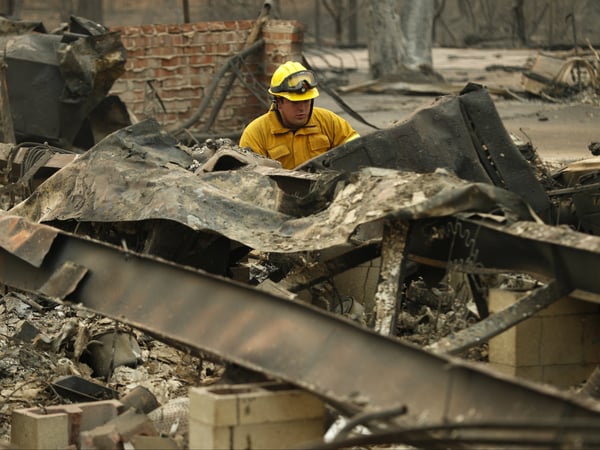 A firefighter looks through a home destroyed by the Camp Fire where human remains were found, Sunday, Nov. 11, 2018, in Paradise, Calif.