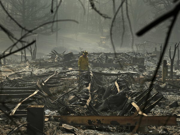 A firefighter searches a trailer park destroyed in the Camp Fire on Friday Paradise, Calif.