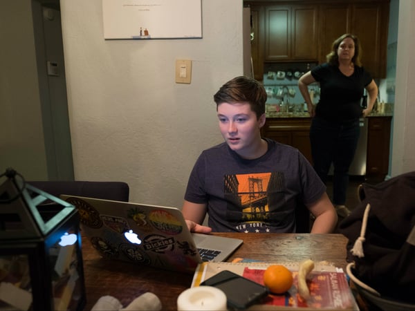Michael Alongi works on homework, while his mother, Jeanne, prepares dinner.