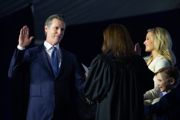 Gavin Newsom takes the oath of office as First Partner Jen Siebel Newsom and their four children stand beside him.