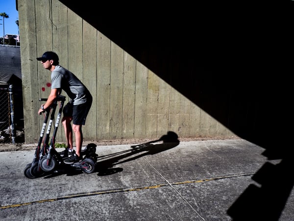 In this July 1, 2018 photo a man rides a Bird scooter carrying several others along the strand in Santa Monica, Calif.