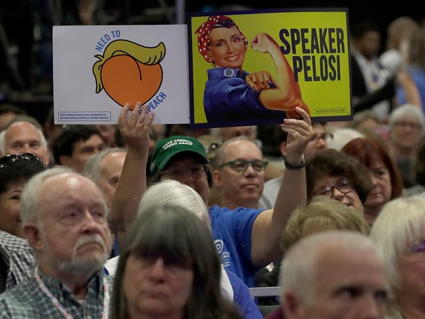 A 2019 California Democratic Party State Organizing Convention attendee holds up signs as Speaker of the House Nancy Pelosi, D-Calif., speaks in San Francisco, Saturday, June 1, 2019.