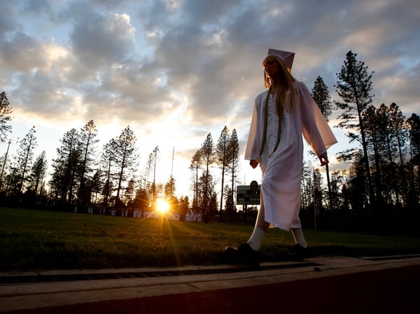 In white cap and gown a graduating senior walks to the graduation ceremonies at Paradise High School in Paradise, Calif., Thursday June 6, 2019. Most of the students of Paradise High lost their homes when the Camp Fire swept through the area.