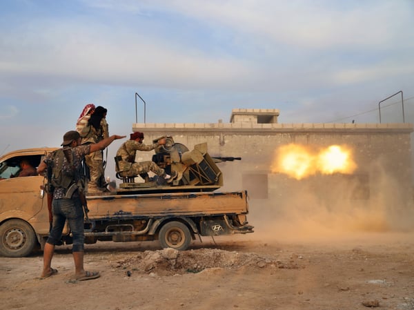 In this Monday, Oct. 14, 2019 photo, Turkey-backed Syrian opposition fighters fire a heavy machine-gun towards Kurdish fighters, in Syria's northern region of Manbij.