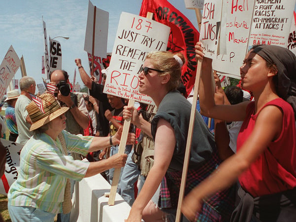 Pro Prop. 187 demonstrator Catherine Nicosia, 74, left, tries to take signs of anti Prop 187 protesters during a rally outside the Federal Building, in the Westwood section of Los Angeles, Saturday, Aug. 10, 1996.
