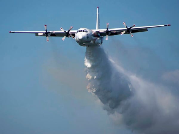 In this undated photo from the Rural Fire Service, a C-130 Hercules plane drops water during a flight in Australia. Officials in Australia on Thursday, Jan. 23, 2020, searched for a water tanker plane feared to have crashed while fighting wildfires.