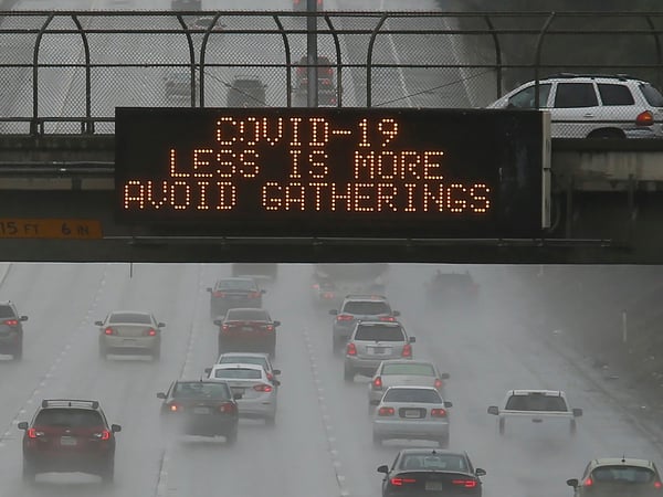 Vehicles pass a COVID-19 warning sign on westbound Highway 50 in Sacramento, Calif., Saturday, March 14, 2020. The California Department of Transportation is displaying public health messages concerning the coronavirus on the state's more than 700 el