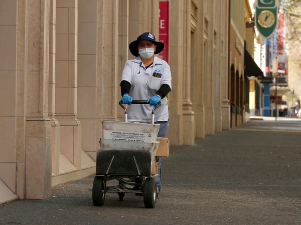 In this Wednesday, March 25, 2020 file photo, U.S Postal carrier Jasmine Yang wears a mask and gloves as preventative measures against the coronavirus, as she delivers the mail in Sacramento.