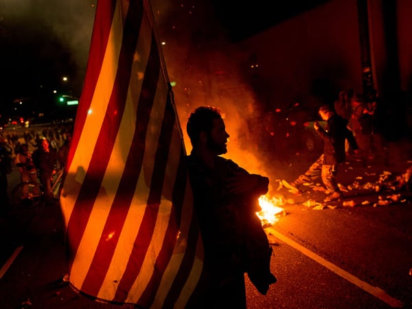 James Cartmill holds an American flag while protesting in Oakland, Calif., on Monday, Nov. 24, 2014, after the announcement that a grand jury decided not to indict Ferguson police officer Darren Wilson.