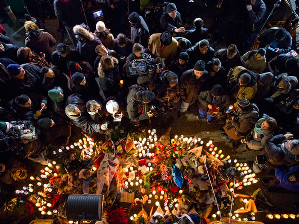 Mourners, members of the media and other gather at a memorial Sunday, Dec. 21, 2014, near the spot where two New York Police Department officers, sitting inside a patrol car the previous day, were shot by an armed man, killing them both.