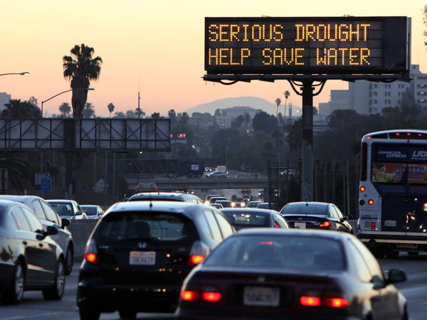 FILE - In this Feb. 14, 2014, file photo, morning traffic makes its way toward downtown Los Angeles along the Hollywood Freewaympast an electronic sign warning of severe drought. 