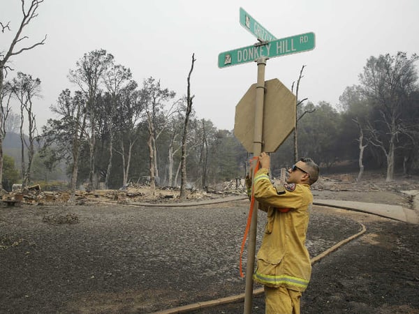 A Sacramento firefighter puts up markings on a street sign below a hillside where a number of homes were destroyed by fire Sunday, Sept. 13, 2015, in Hidden Valley, Calif.