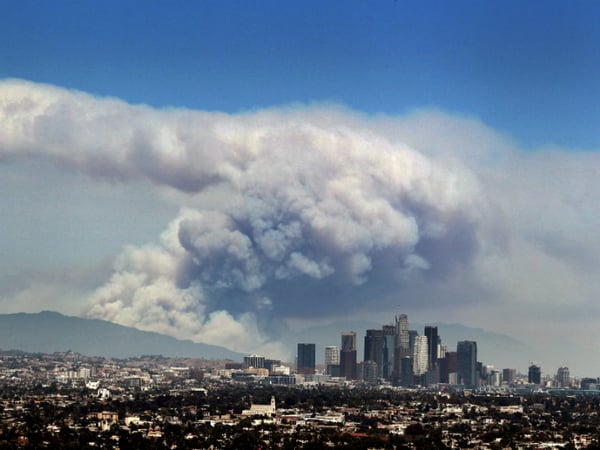 Smoke from wildfires burning in Angeles National Forest fills the sky behind the Los Angeles skyline on Monday, June 20, 2016.