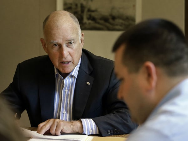 FILE - In this July 7, 2017, file photo, California Gov. Jerry Brown discusses a bill with Chris Ferguson, right, a principal program budget analyst. 