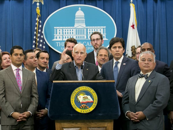 Gov. Jerry Brown, center, flanked by lawmakers from both sides of the aisle, speaks of the passage of a pair of climate change measures, Monday, July 17, 2017, in Sacramento, Calif.