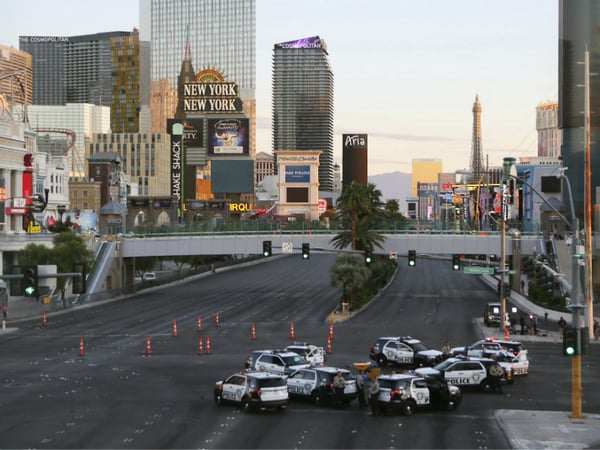 A roadblock is shown through a gap in a glass partition at the corner of Las Vegas Boulevard and Tropicana Avenue, Monday, Oct. 2, 2017, in Las Vegas. A mass shooting occurred late night Sunday at a music festival on the Las Vegas Strip. 