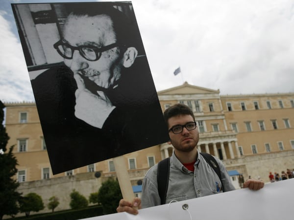 A protester holding a placard with the image of Greek writer and philosopher Nikos Kazantzakis, writer of the novel "Zorba the Greek", takes part in a protest in front of the Parliament in Athens, Friday, June 14, 2013.