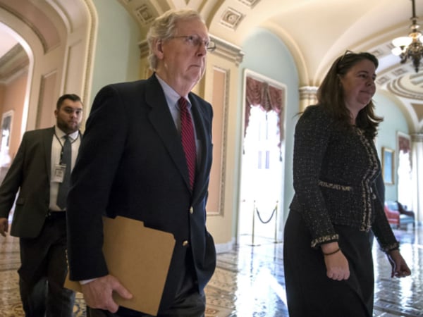 Senate Majority Leader Mitch McConnell, R-Ky., accompanied at right by Secretary for the Majority Laura Dove, walks to the chamber as Republicans in the House and Senate plan to pass the sweeping $1.5 trillion GOP tax bill on party-line votes. 