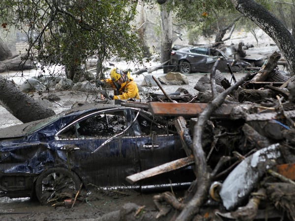 A member of the Long Beach Search and Rescue team looks for survivors in a car in Montecito, Calif., Tuesday, Jan. 9, 2018.