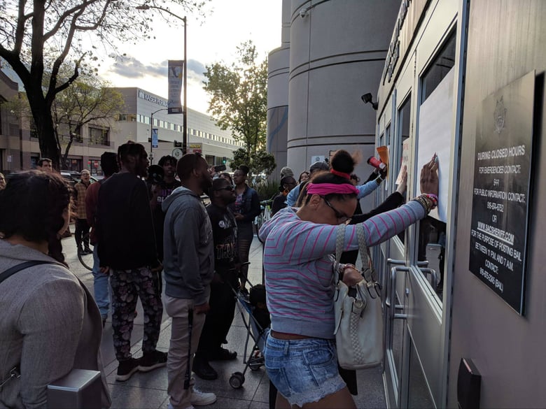Demonstrators hold signs in front of the main Sacramento County jail after two women were forcibly arrested by police on Thursday.