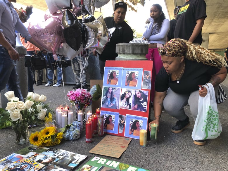 Malika Harris places a candle down for her sister Nia Wilson at a makeshift memorial outside the MacArthur Bay Area Rapid Transit station, Monday, July 23, 2018, in Oakland, Calif. 
